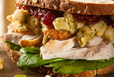 A Thanksgiving leftover sandwich, with turkey, stuffing and cranberry sauce piled between pieces of bread