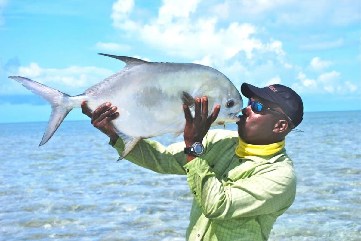 Prescott Smith holding a permit fish he caught in the Bahamas up to his face