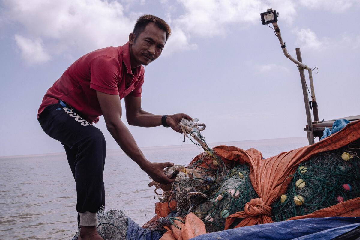 A fisher leaning on the edge of their boat 