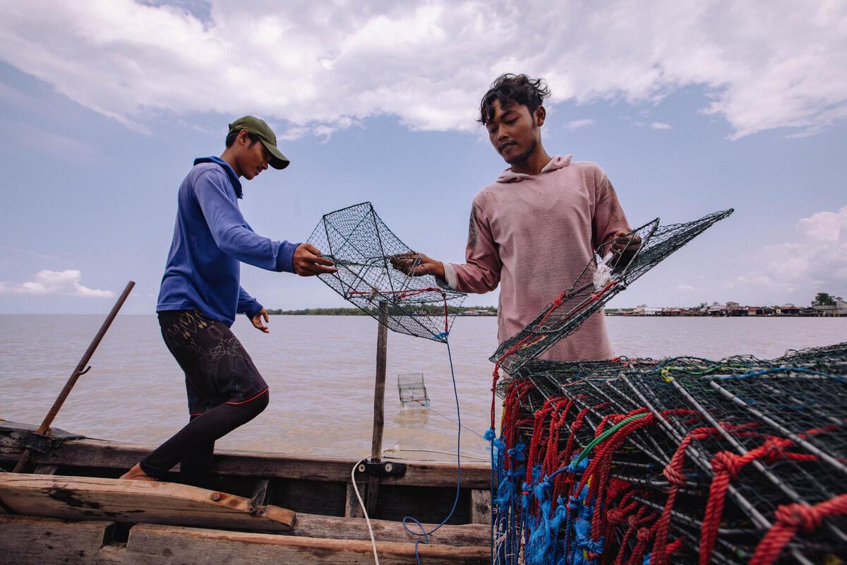 Two fishers on their boat holding up nets