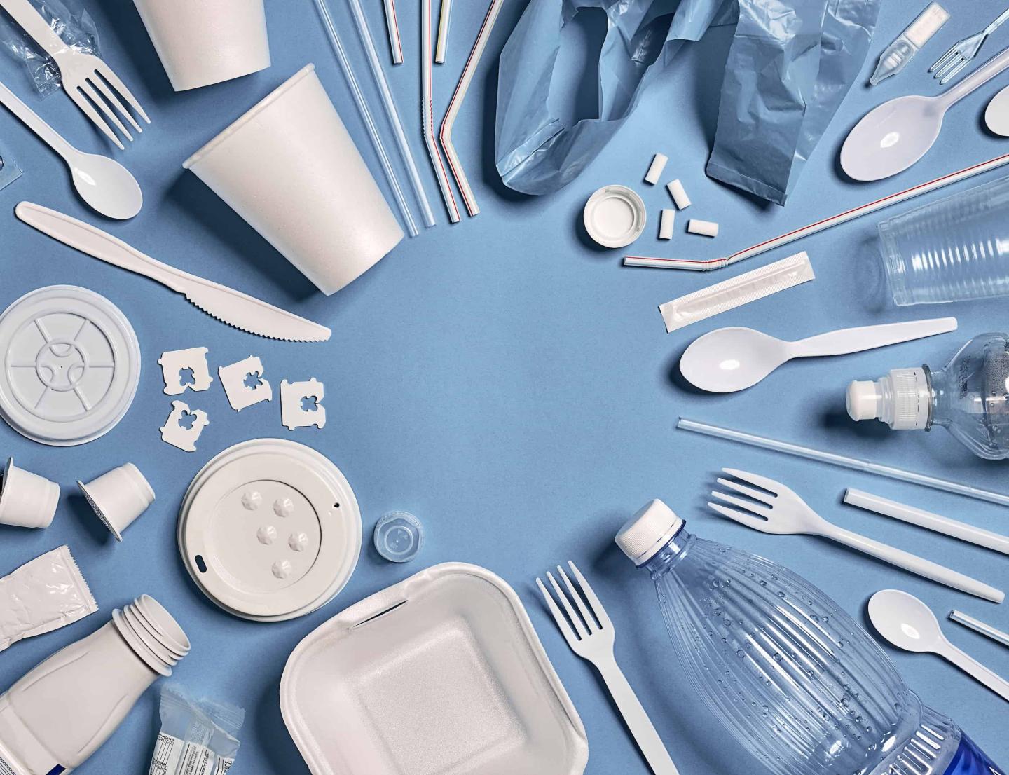 A bunch of plastic cutlery and assorted items on a blue tablecloth