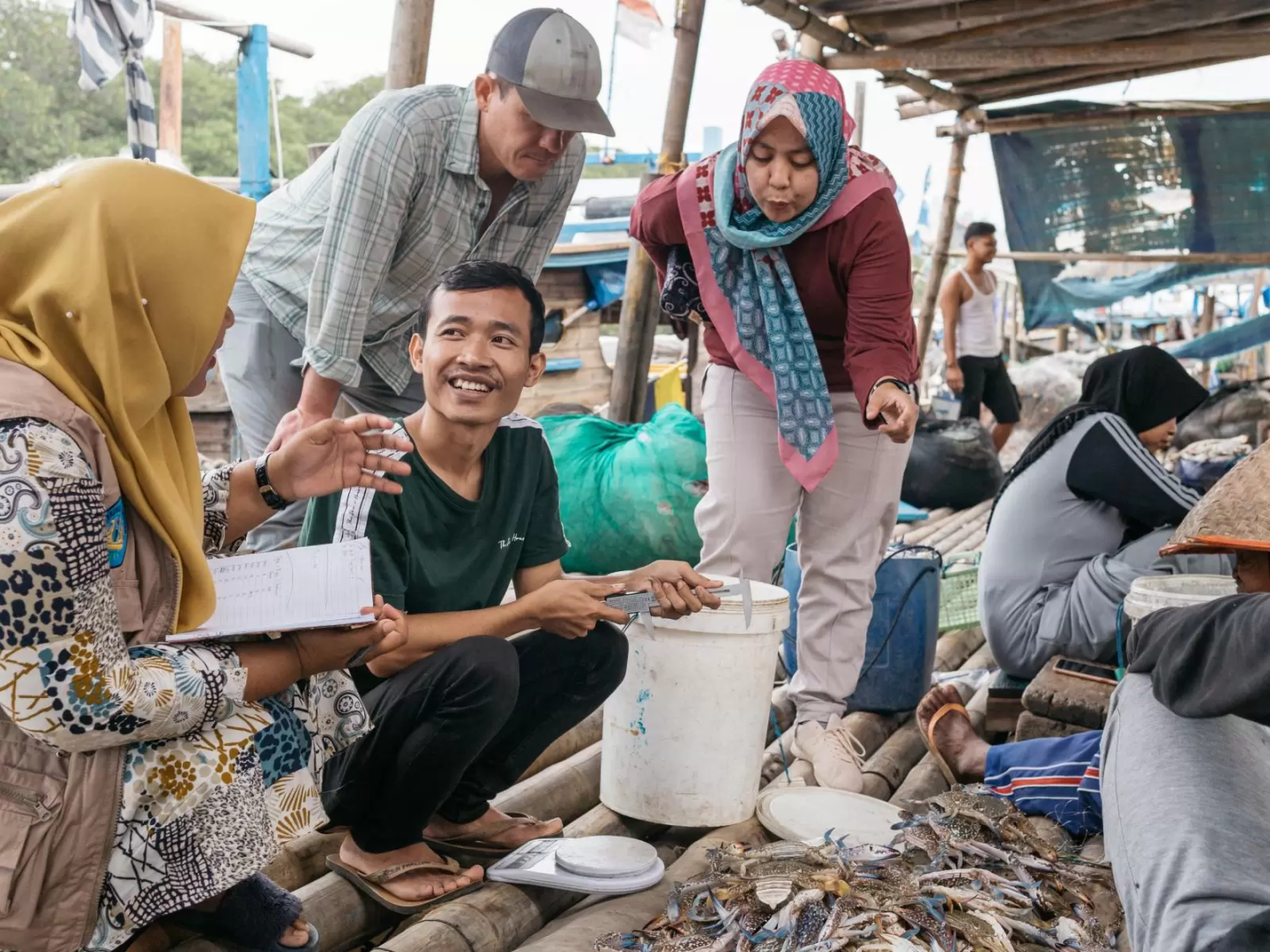 Indonesia fisheries enumerator Ayu Listiani Putri assesses the health of the blue swimming crab fishery in Lampung Province with other people standing around
