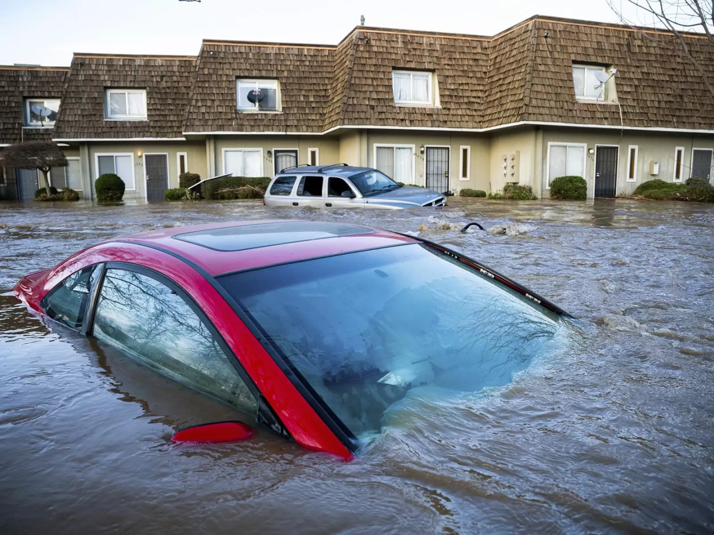 Car submerged in flood water. Row of houses in the background