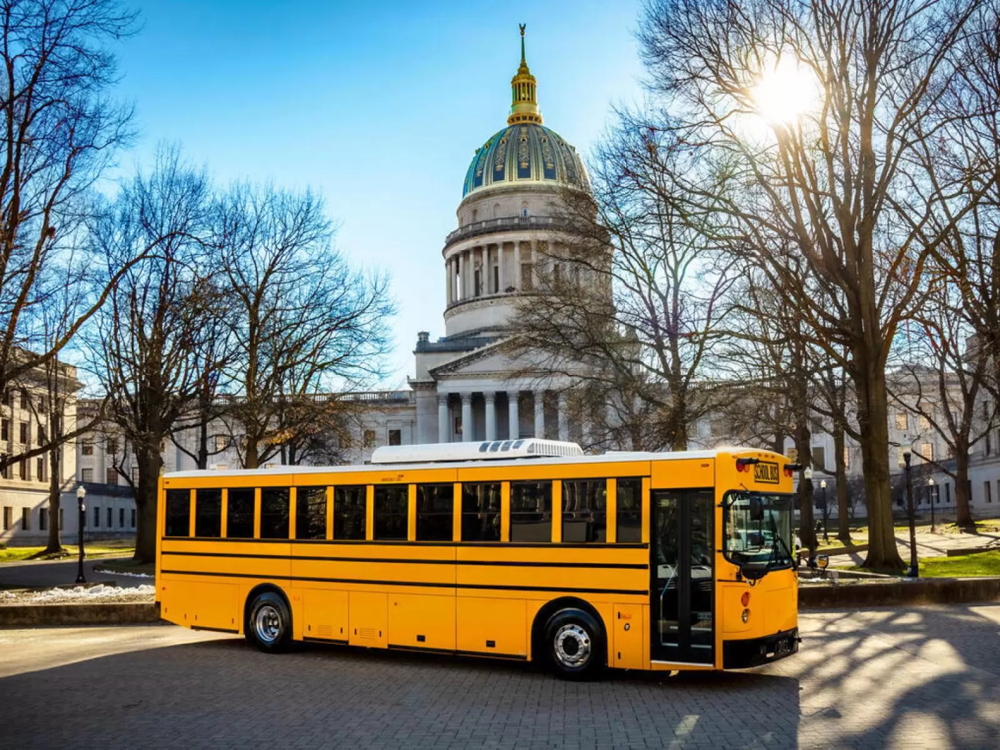 An electric yellow school bus parked in front of the U.S. Capitol building