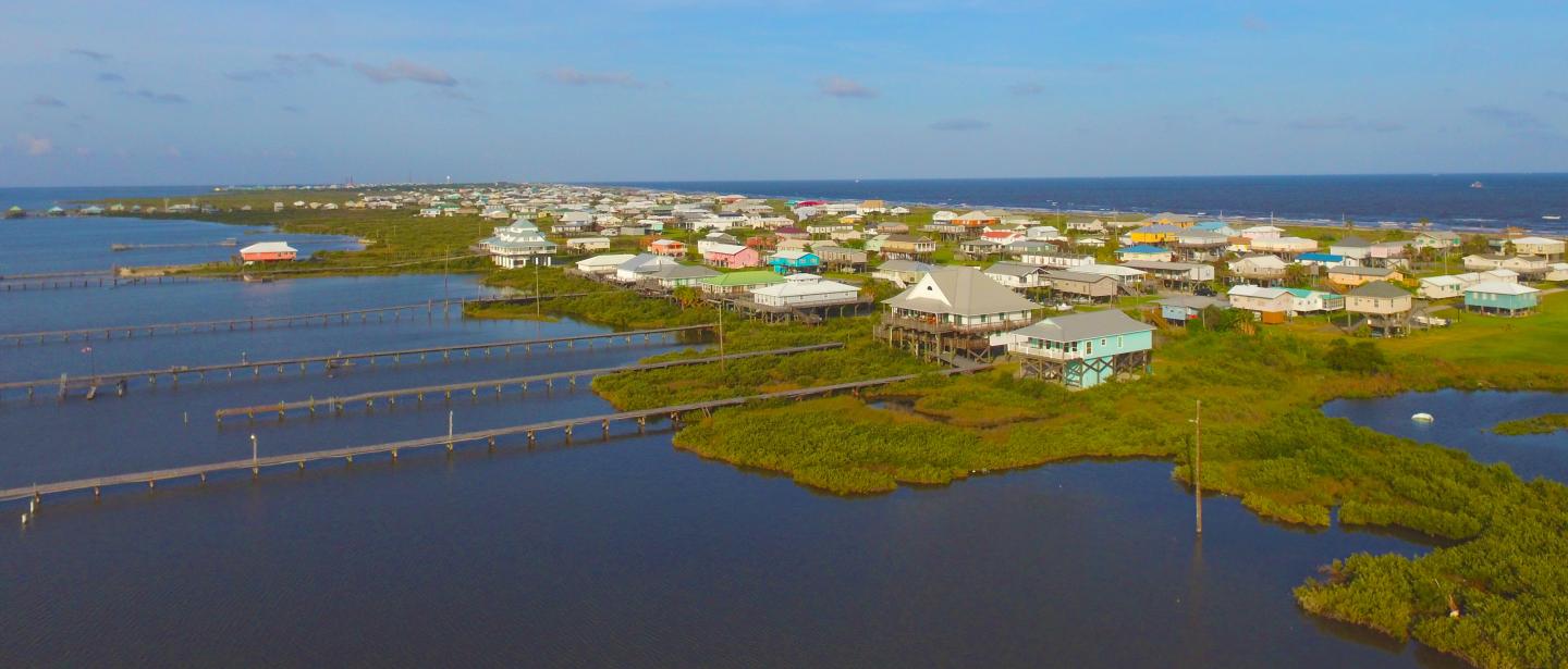 A coastal community, surrounded by water, with houses built on stilts