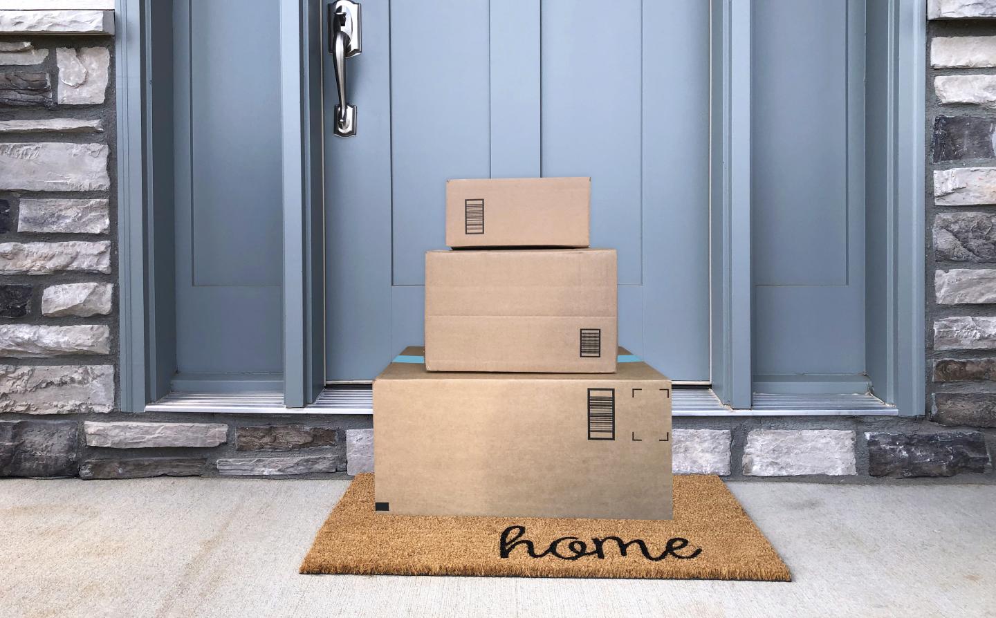 Pile of cardboard boxes delivered to a household with a blue front door