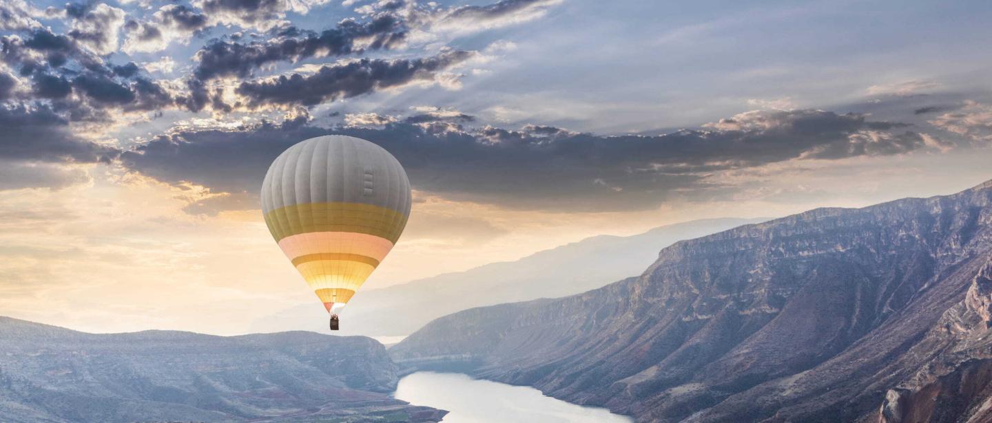 Hot air balloon flies over scenic river valley