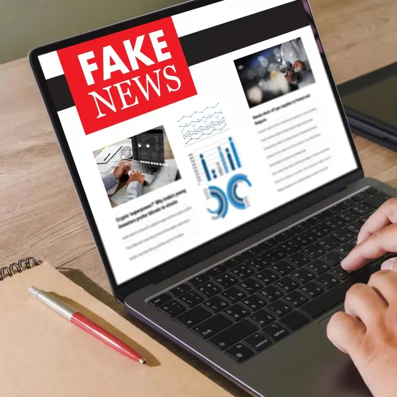 an open laptop displaying a newspaper header displaying the words Fake News in white lettering on a red background