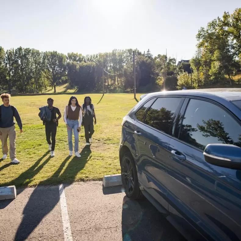 Four young people walking up to an electric vehicle