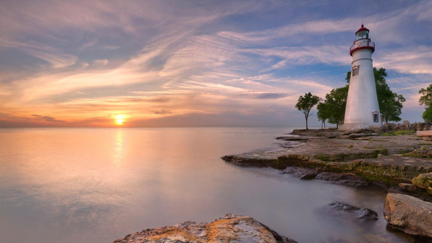 A lighthouse on the banks of Lake Eerie while the sun rises in the distance — the sun could be setting, but it just gives off rising vibes, you know what I mean?