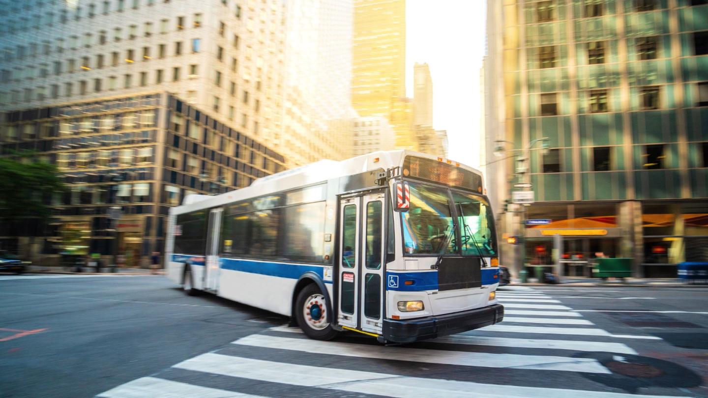 A bus making a turn through a crosswalk on a New York City street