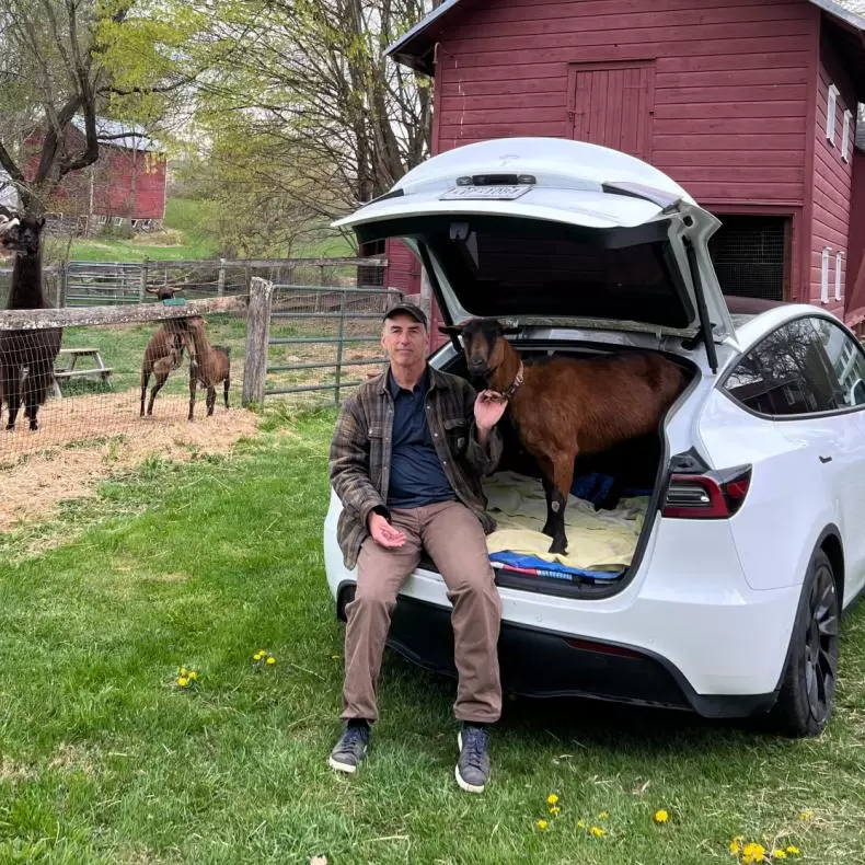 Robert McKeon sits inside his Tesla with one of his goats