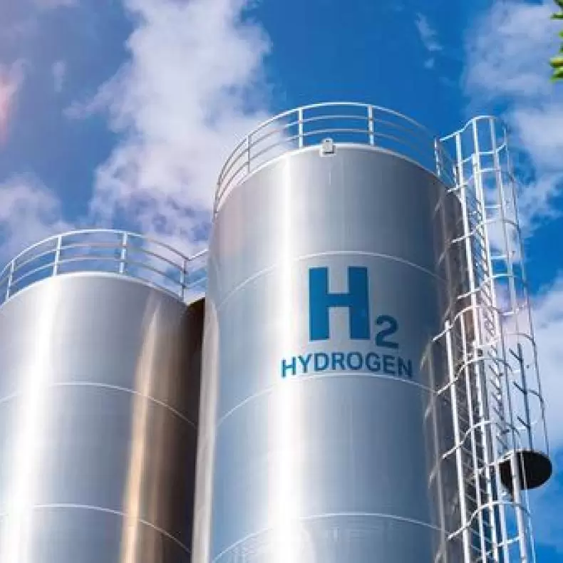 Tall cylindrical steel hydrogen tanks against a blue sky