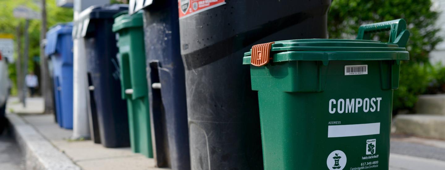 A row of compost and trash and recycling bins