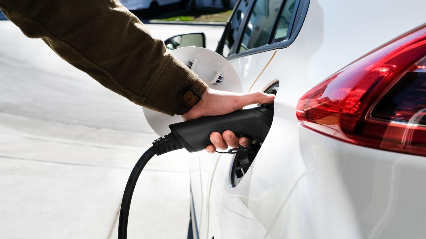 Someone inserting a charger into an electric car