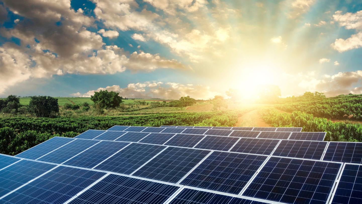 A sprawling field of solar panels with a comically bright sunrise in the distance