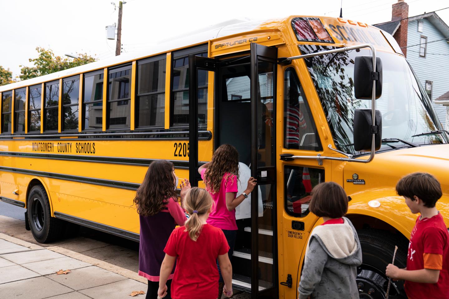 Kids file onto a yellow school bus