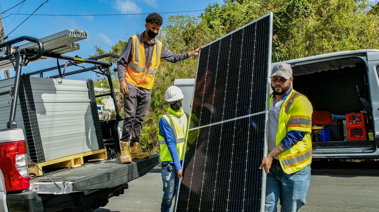 Three men moving a solar panel