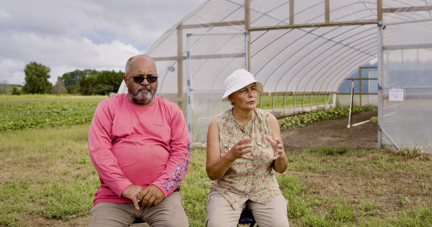 Fifth generation farmers Millard and Connie Locklear sit in front of their greenhouse