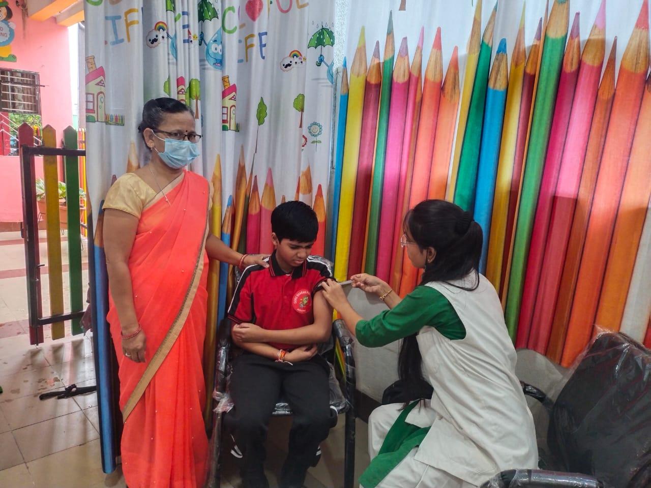 An ASHA worker injecting a young person with a vaccine