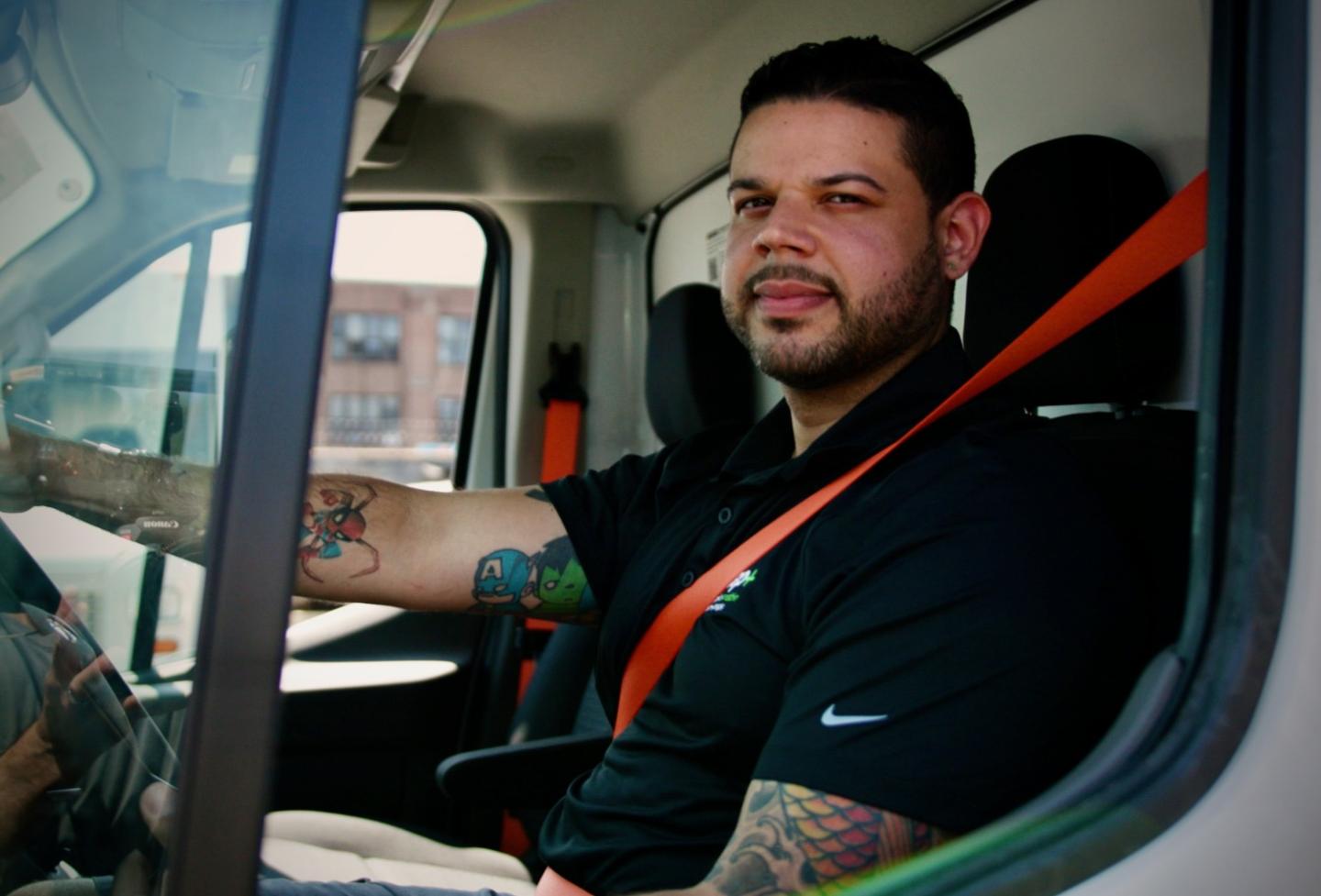 Arnel Sencion sitting in the cab of his electric delivery truck