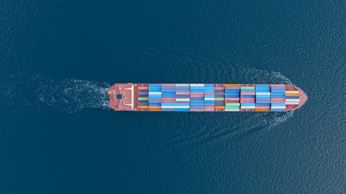 An overhead shot of a shipping container laden boat traveling in open water