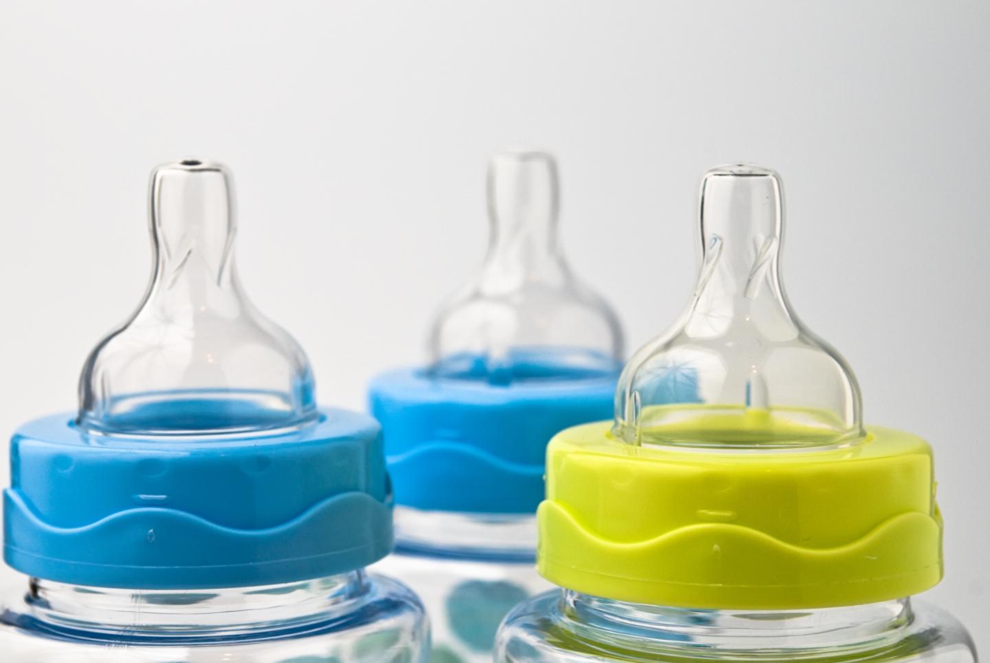 A close up of the tops of three baby bottles