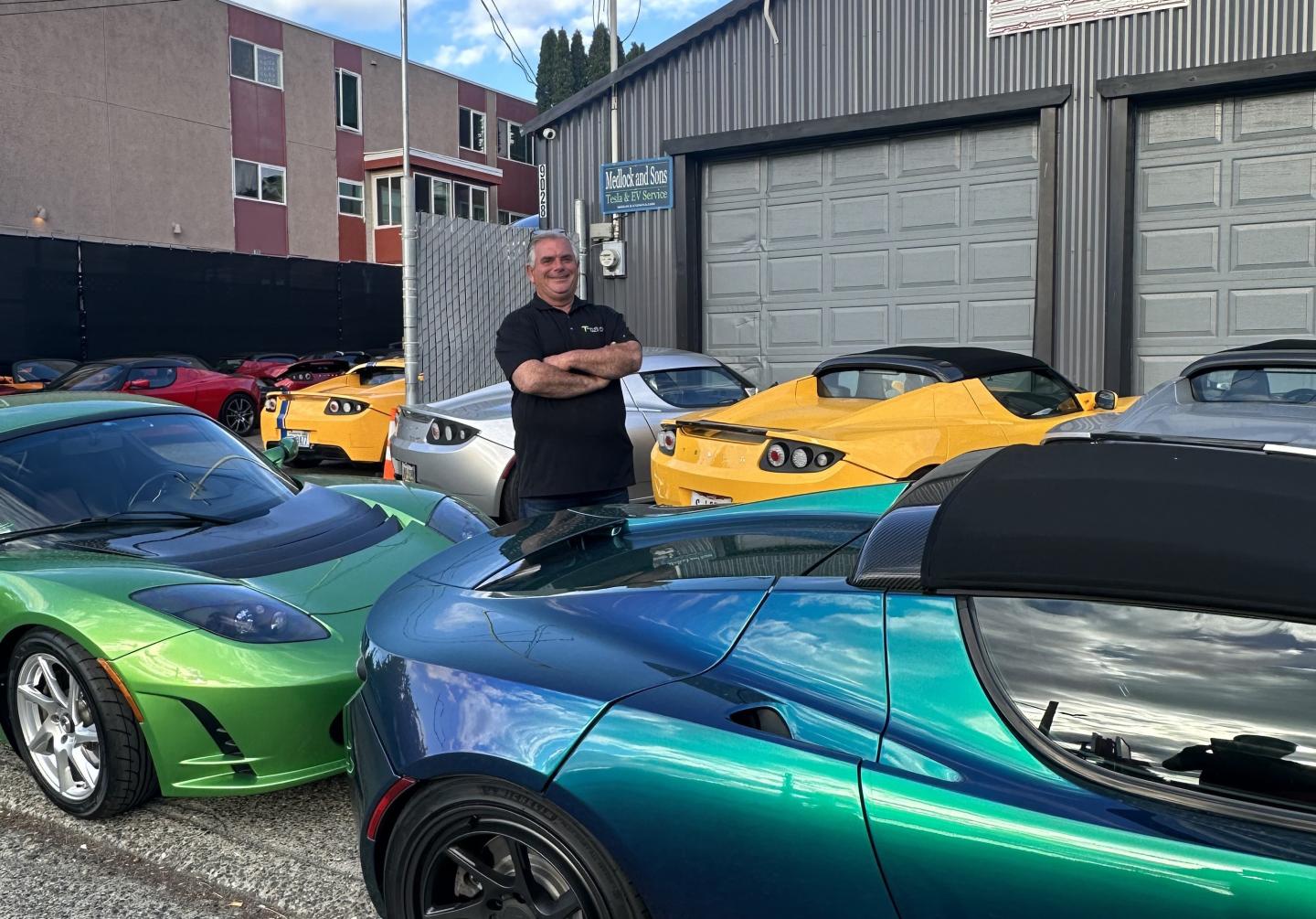 Carl Medlock standing in a row of electric vehicles