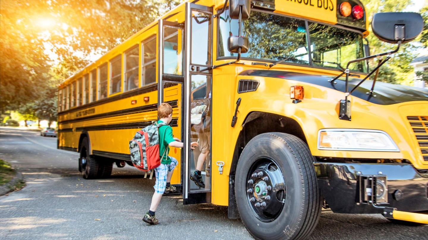 Children climbing aboard a big yellow school bus