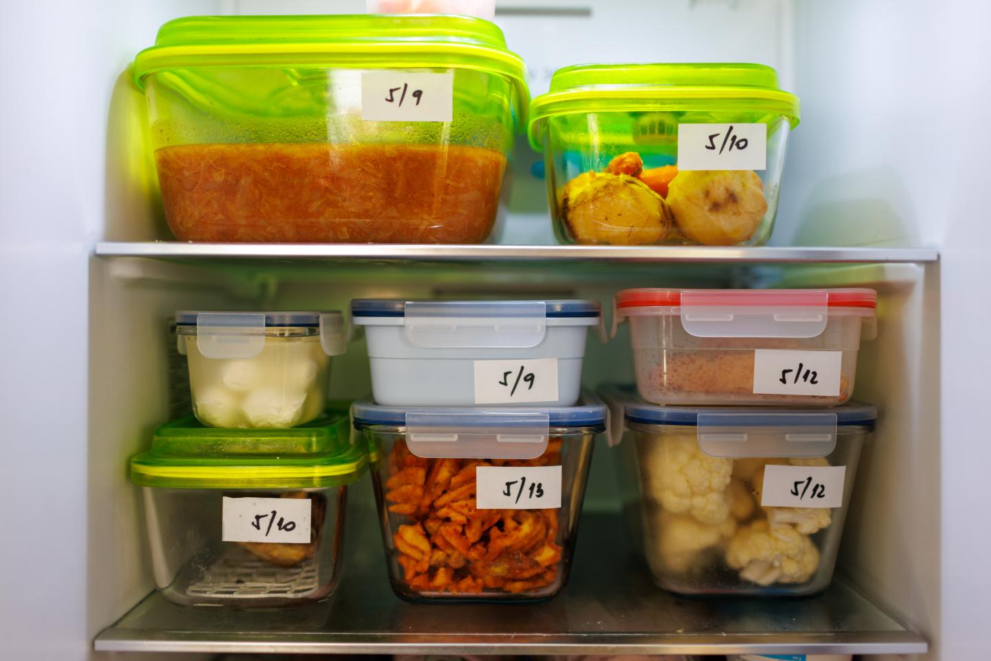 Leftovers in the refrigerator stacked in clear containers and labeled with dates 