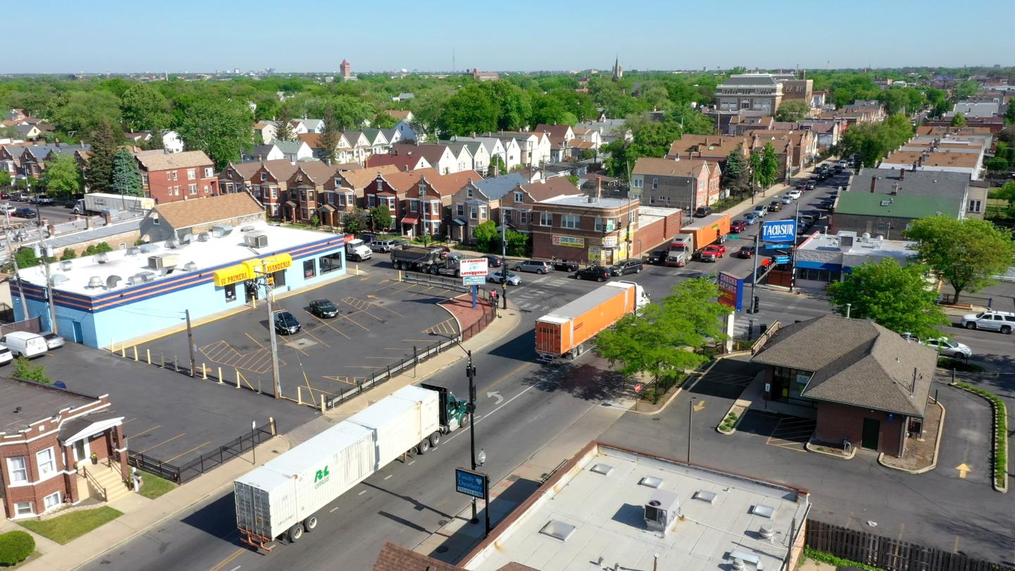 A Little Village intersection where several large trucks are driving through