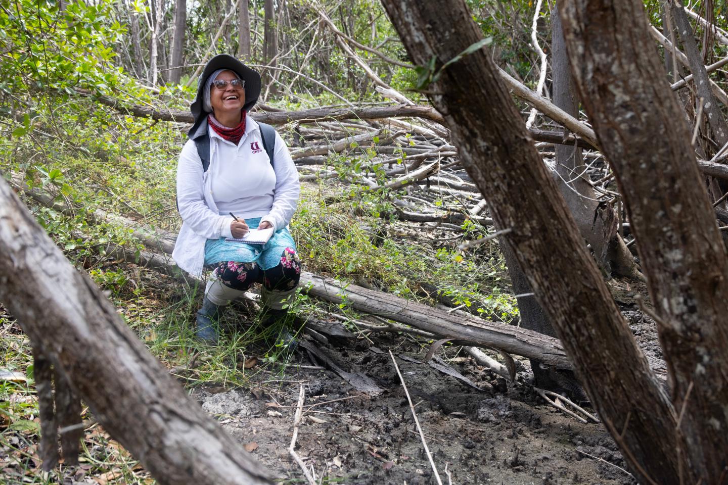 Dr. Natalia Molina looks up at a mangrove smiling
