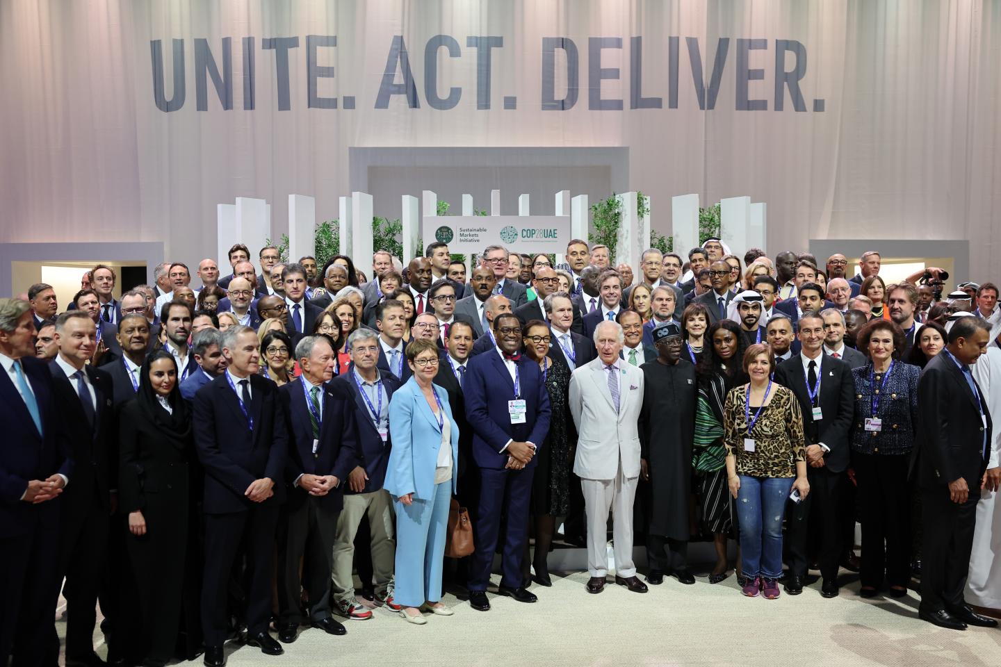 A large group of world leaders standing in front of a sign that says "Unite. Act. Deliver." at COP28