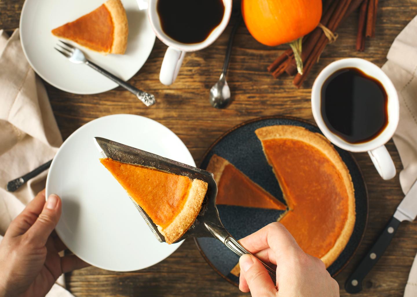 Slices of pumpkin pie with cups of coffee