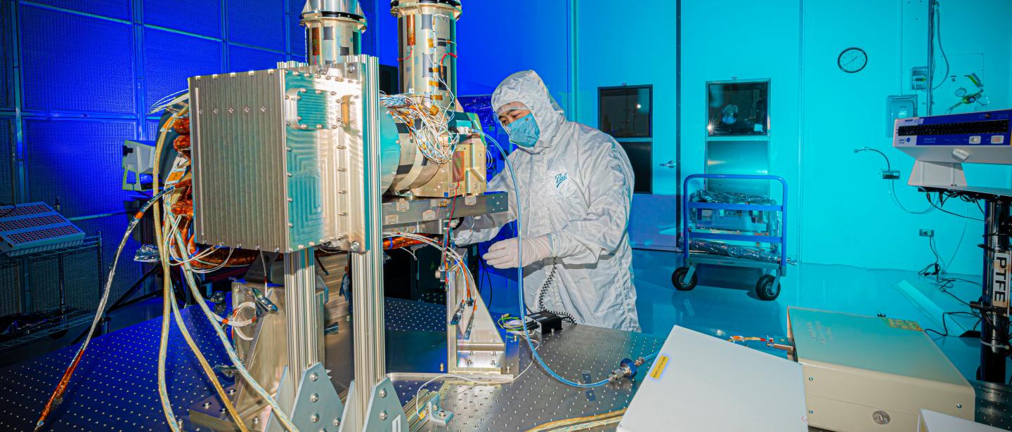 A scientist inspects the components of a satellite 