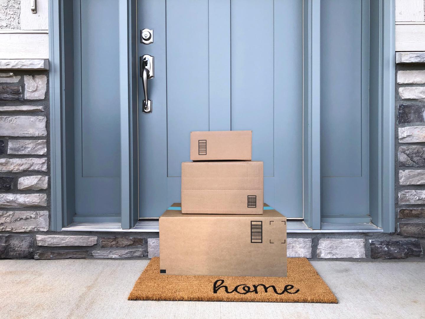 Pile of cardboard boxes delivered to a household with a blue front door