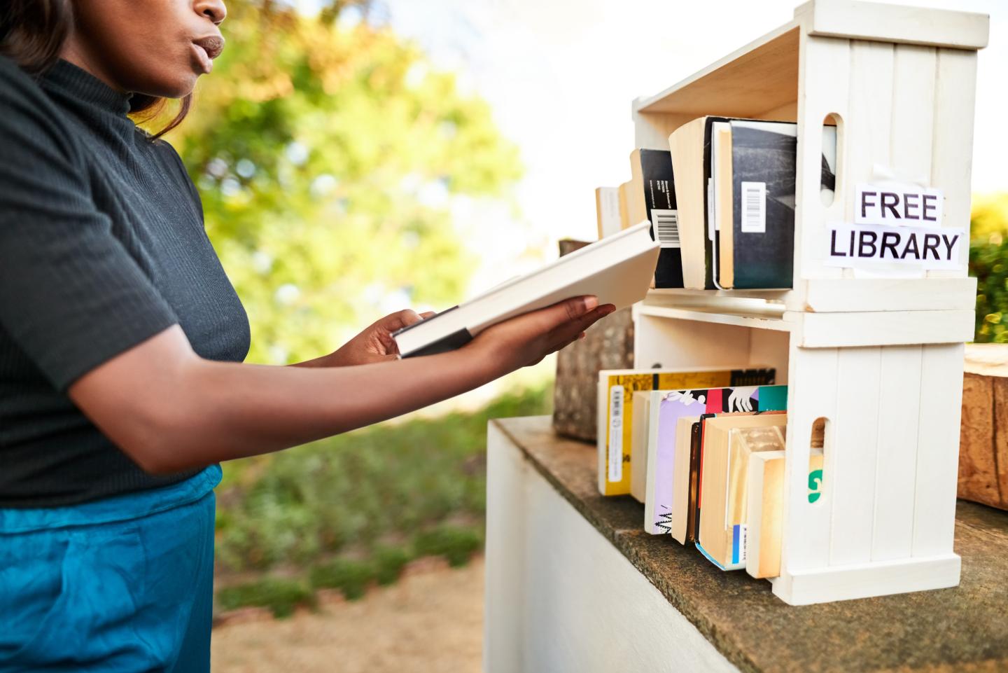 A person excitedly pulls a book from a bookshelf marked Free Libary