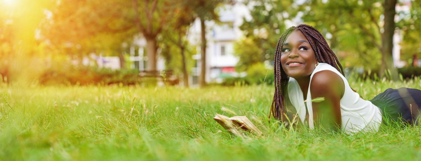 A person laying in grass reading a book