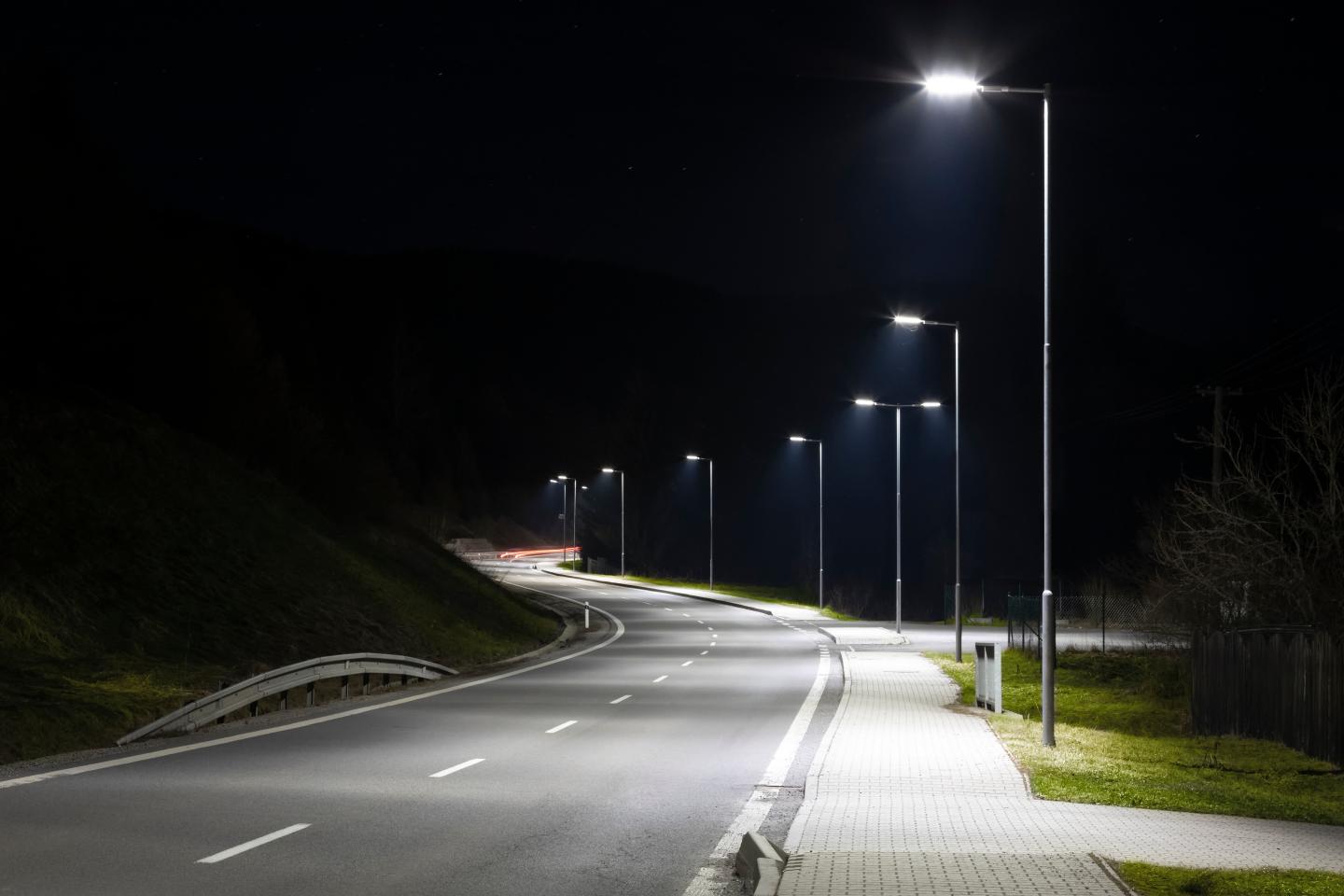 A row of white, LED street rights on an empty road at night