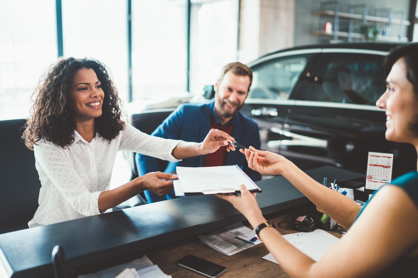 A person signing paperwork to get a new car