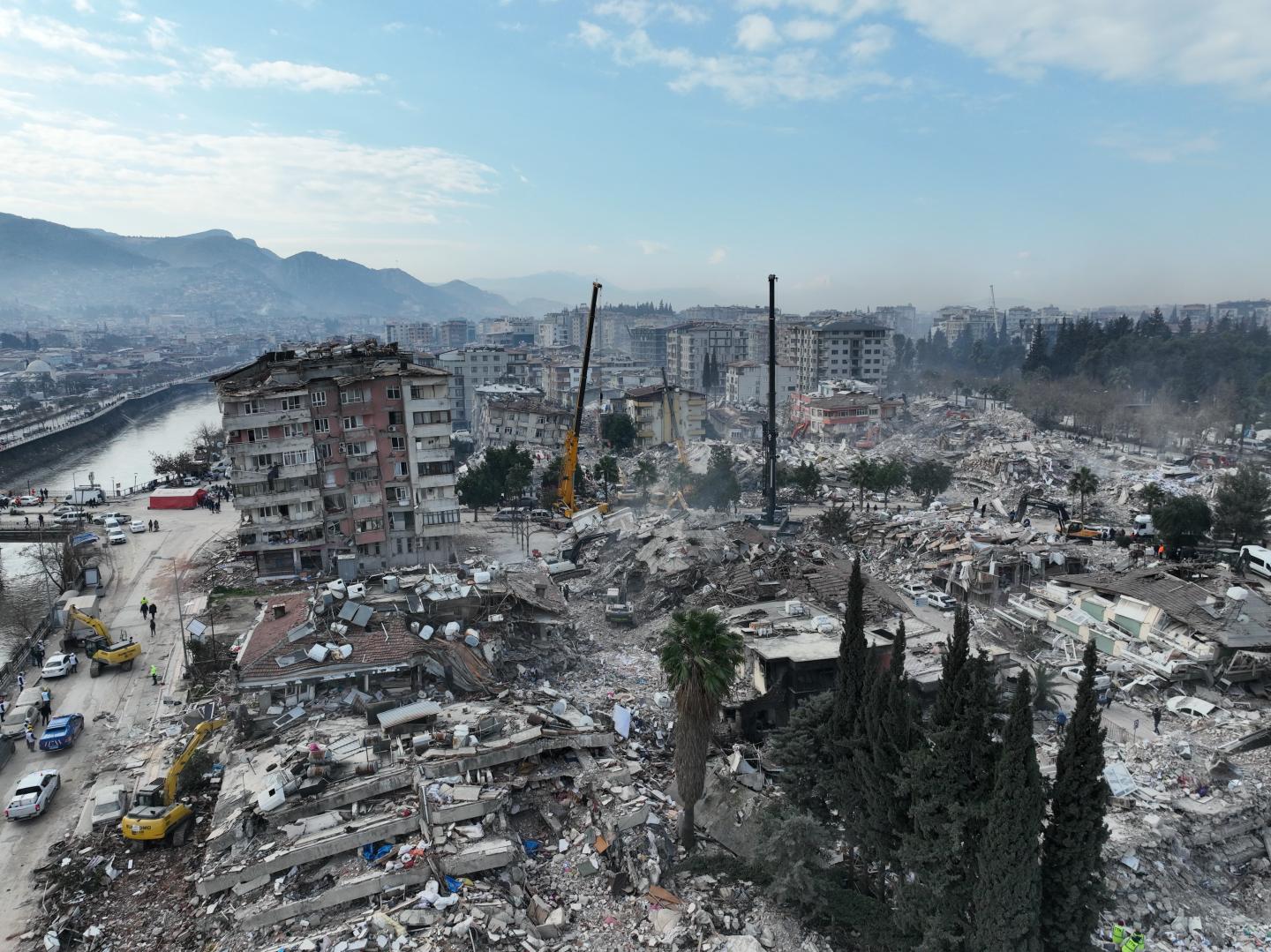 The aftermath of an earthquake in Turkey with many buildings toppled and cranes helping clear debris