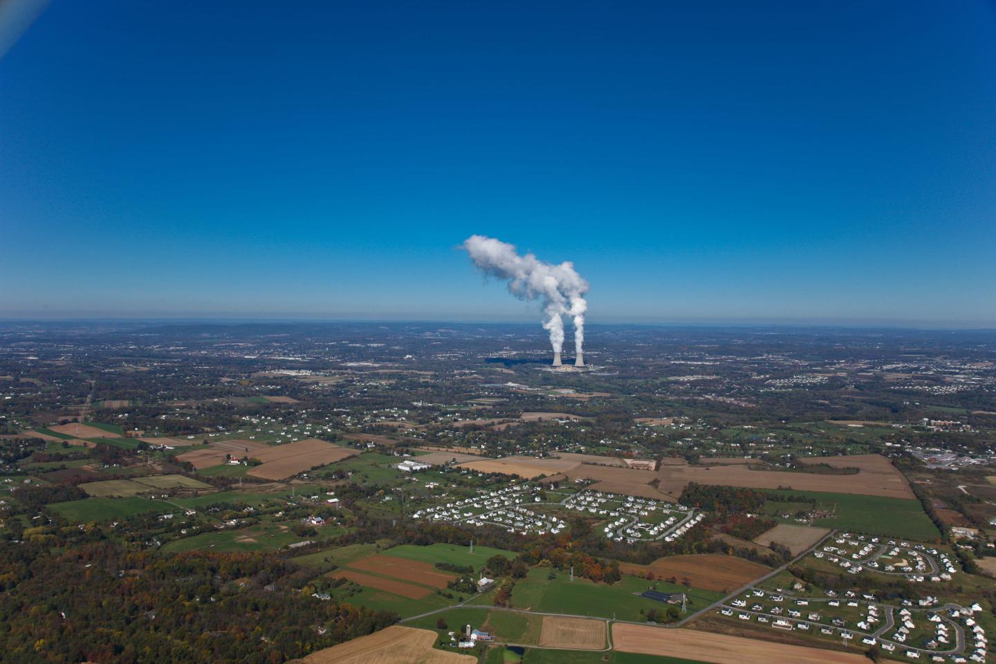 A high up shot of Pennsylvania with two plumes of smoke coming out of a power plant in the distance