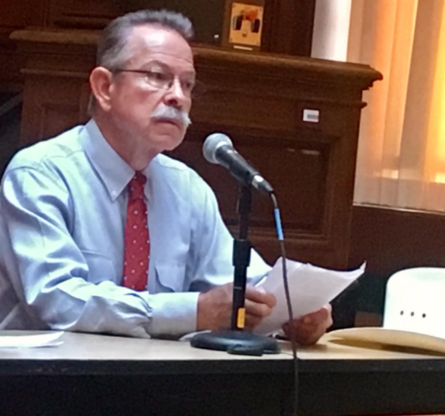 Don Schreiber reading testimony into a microphone