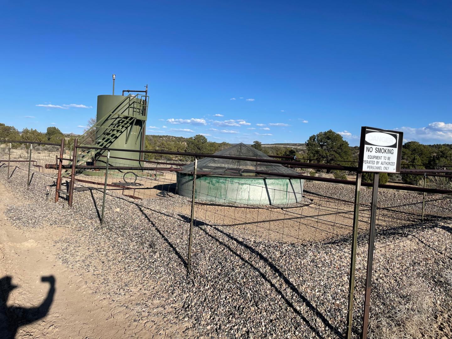 An oil and gas well with the person taking the photograph's shadow also slightly in frame