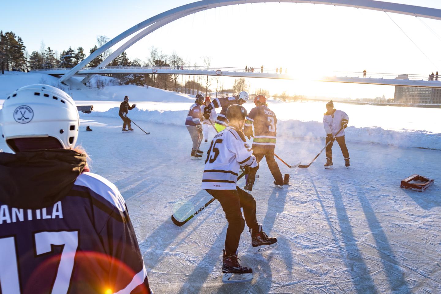 People playing hockey on a frozen pond outdoors