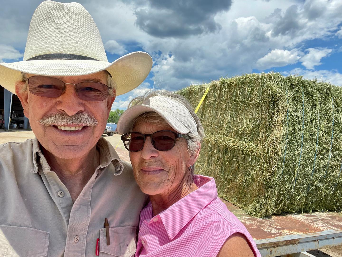 Don and Jane Schreiber standing in front of a bale of hay