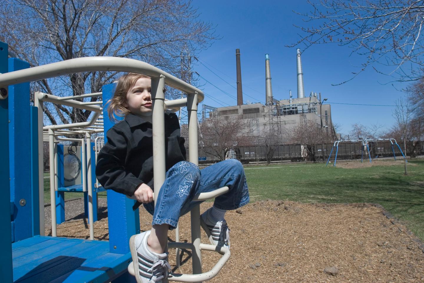 A four-year-old plays on a park next to a coal-fired power plant