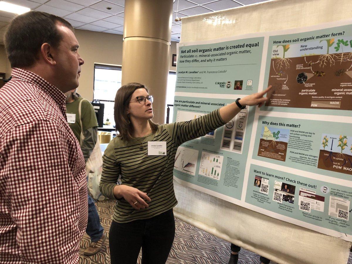 Jocelyn Lavallee pointing to an academic poster showing her study on soil