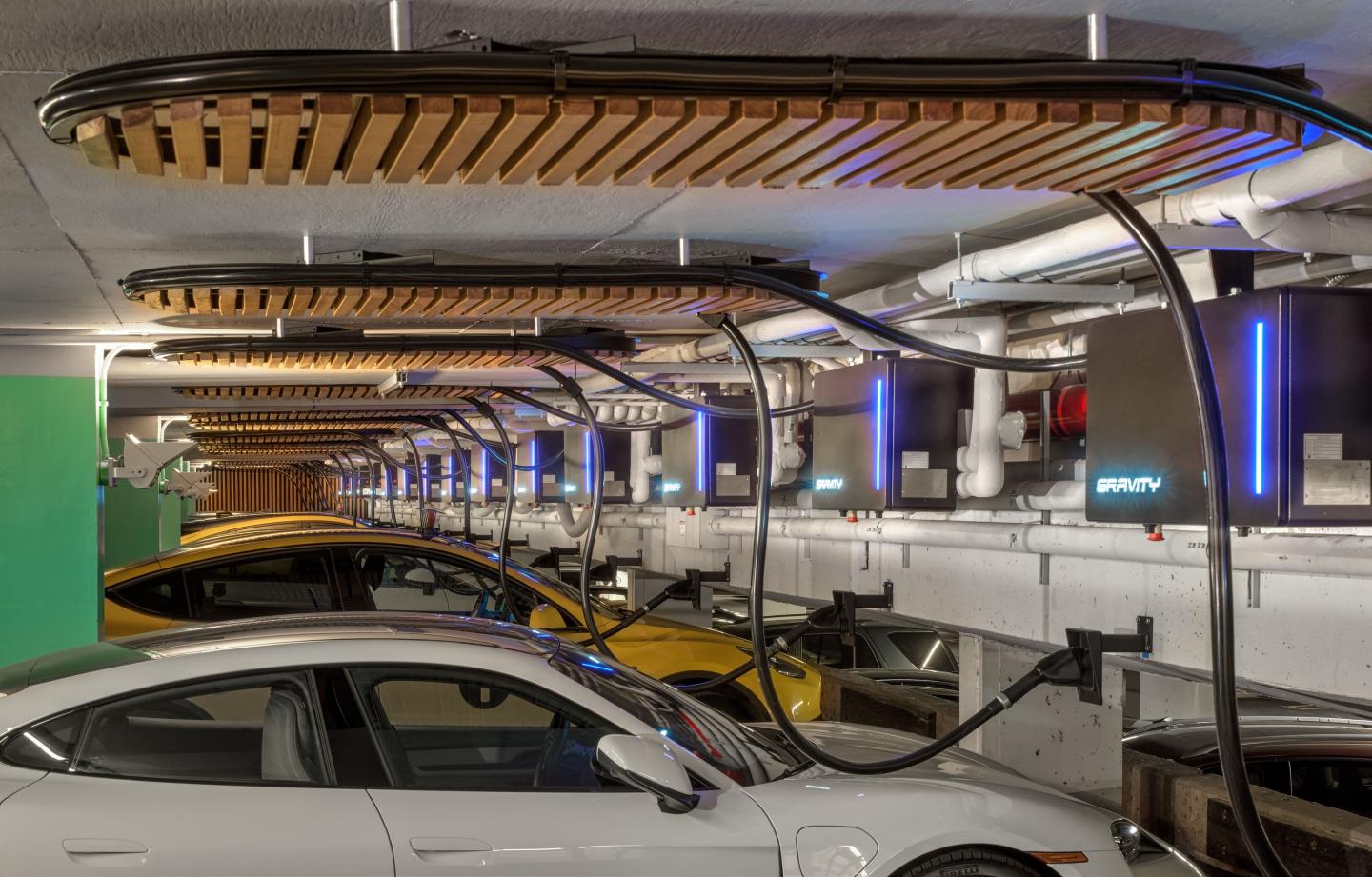 A row of electric cars plugged into chargers overhead