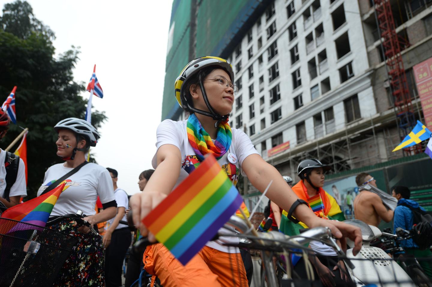 Women riding bikes with rainbow flags attached to them at a Vietnamese Pride festival